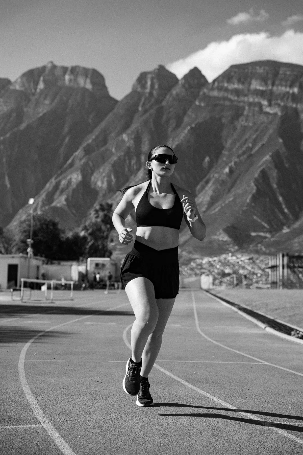 Corredora entrenando en una pista de atletismo frente a la sierra de Monterrey