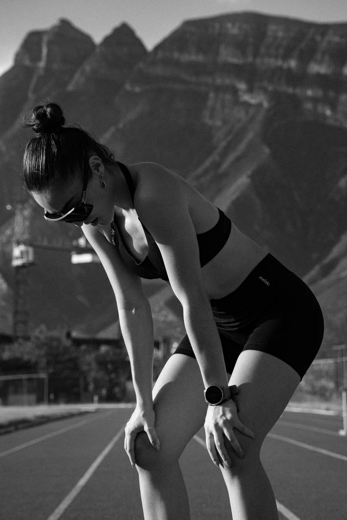 Atleta recuperando el aliento con las manos en las rodillas sobre una pista de atletismo