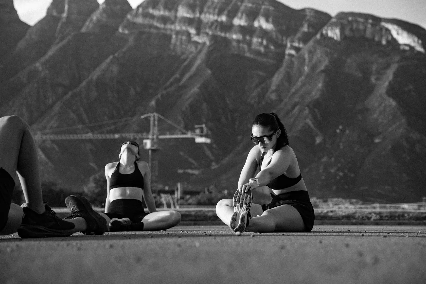 Tres atletas sentados en la pista frente a las montañas de Monterrey